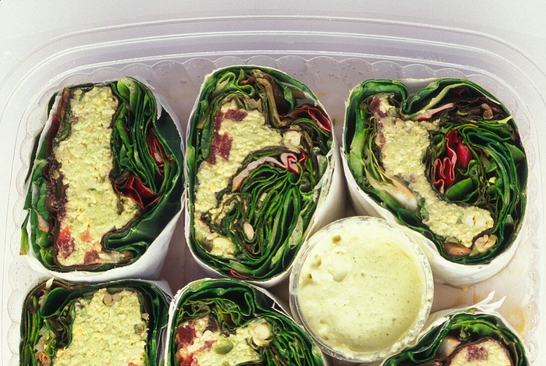 Vegetarian wraps filled with raw vegetables in plastic containers