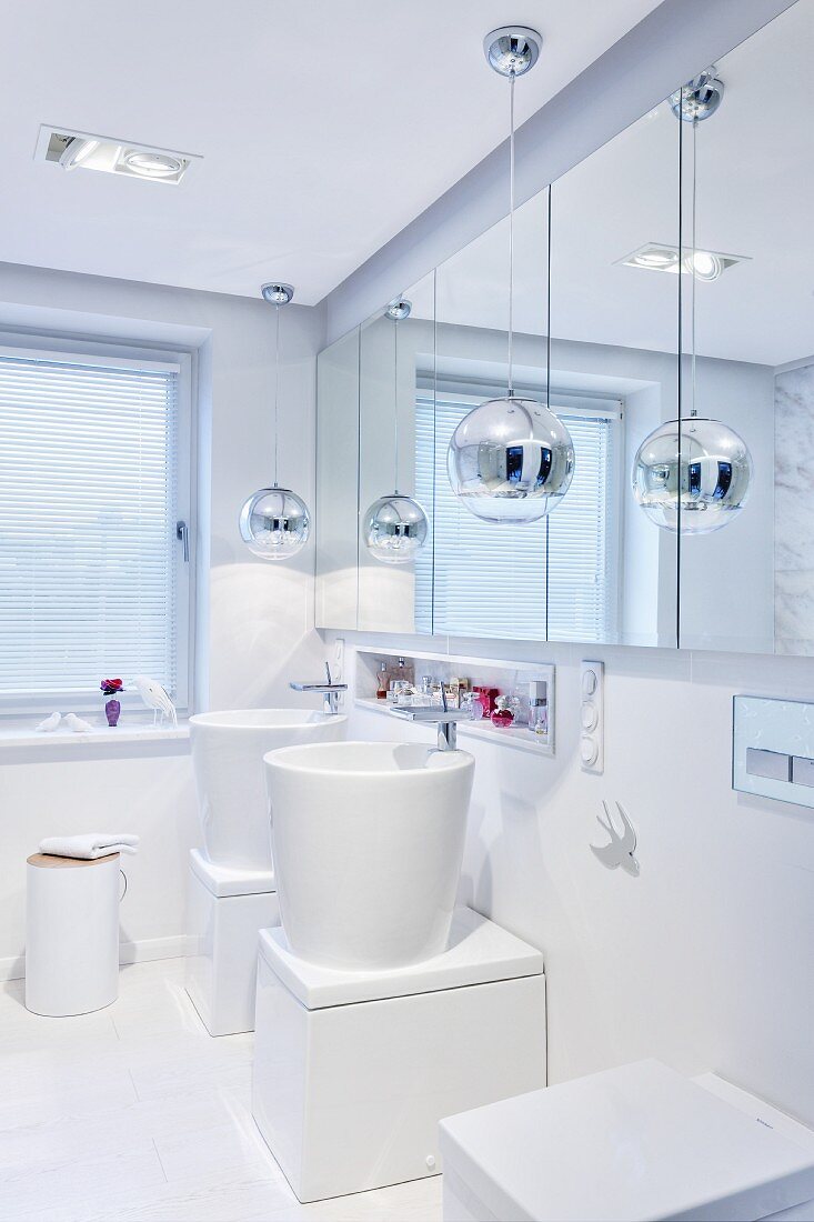 Designerbad, extravagante Waschtische vor Spiegelschrank an Wand, Pendelleuchten mit verchromtem Kugelschirm