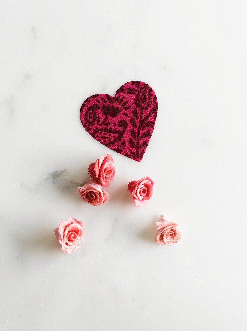 A paper heart and pink marzipan roses as cake decoration