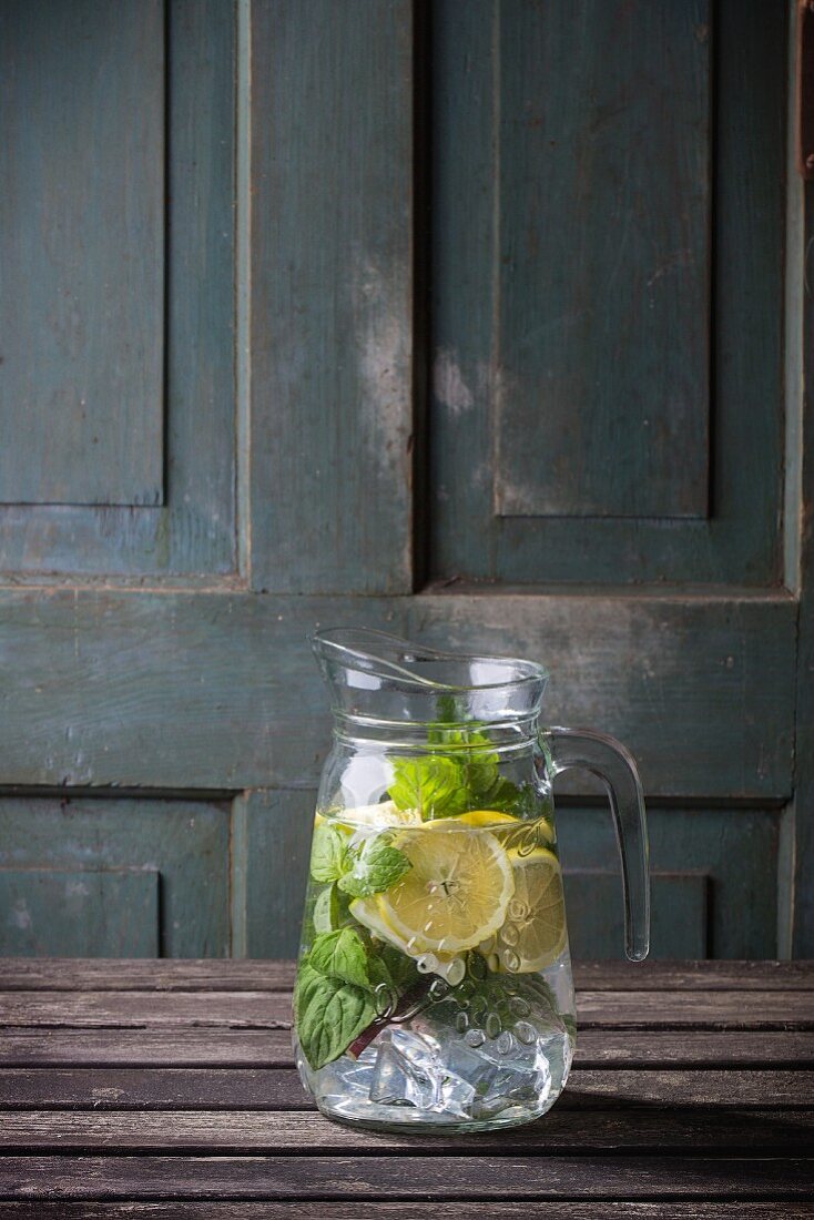 A jug of homemade lemonade with lemon and mint