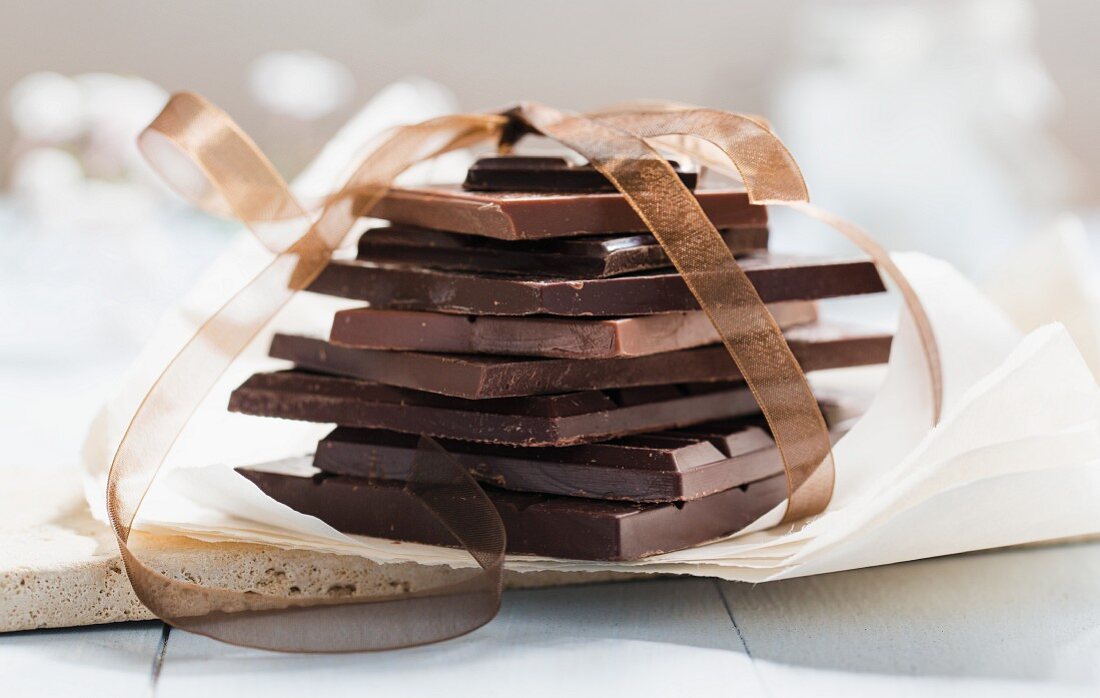 Verschiedene Schokoladenstücke mit Geschenkband umwickelt