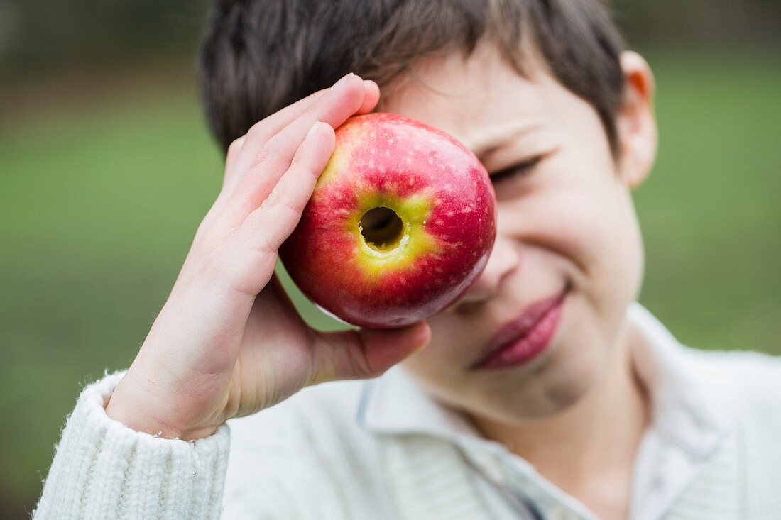 Junge schaut durch entkernten Apfel