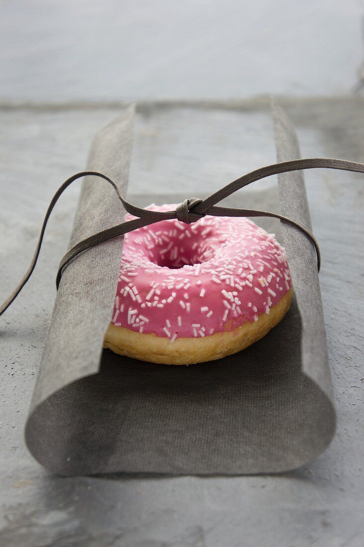 Donut mit Himbeerglasur verpackt in Seidenpapier