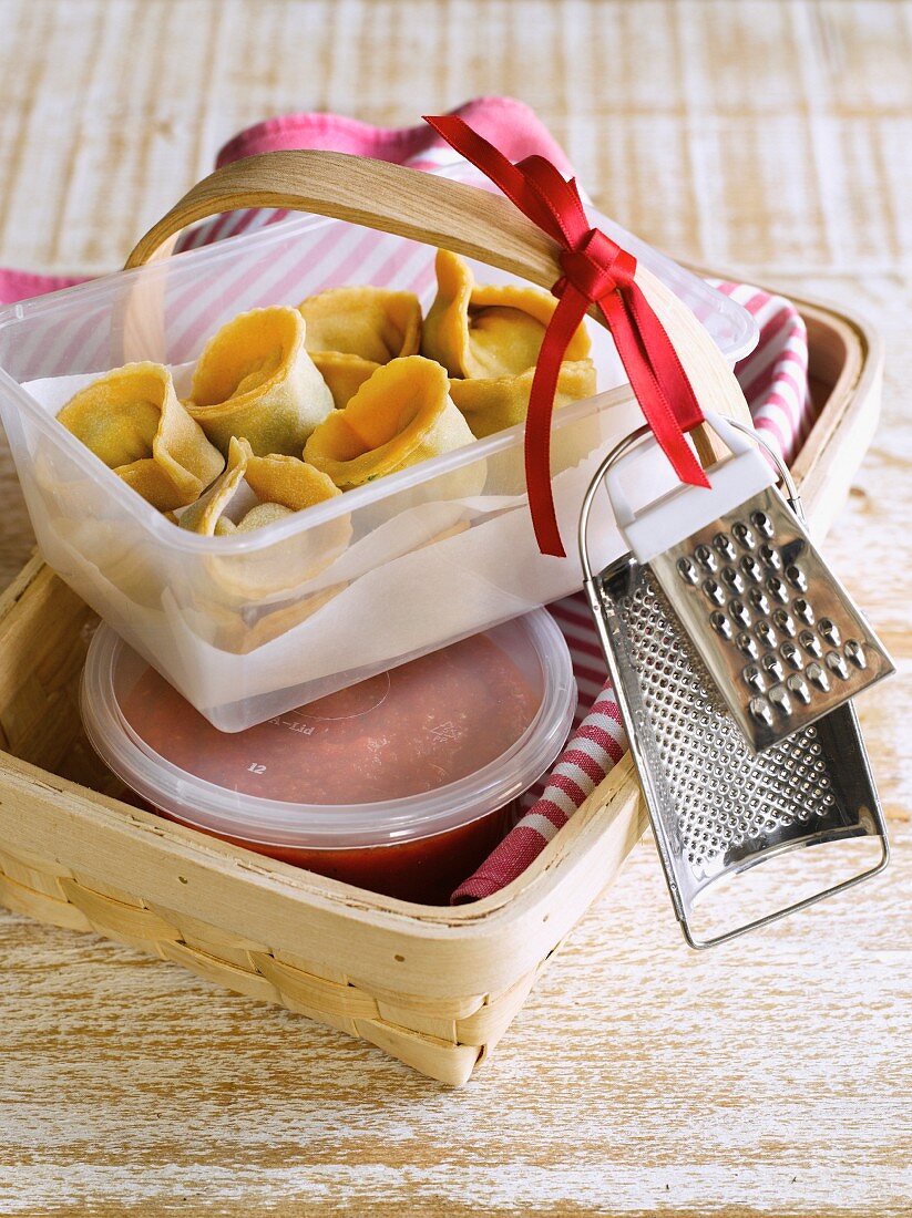 Homemade pasta parcels with tomato sauce as a gift in a wooden basket