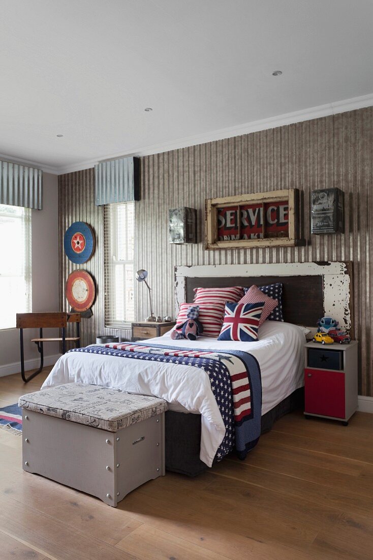 Vintage-style teenager's bedroom with Union-Flag scatter cushions on bed and old wooden trunk at foot