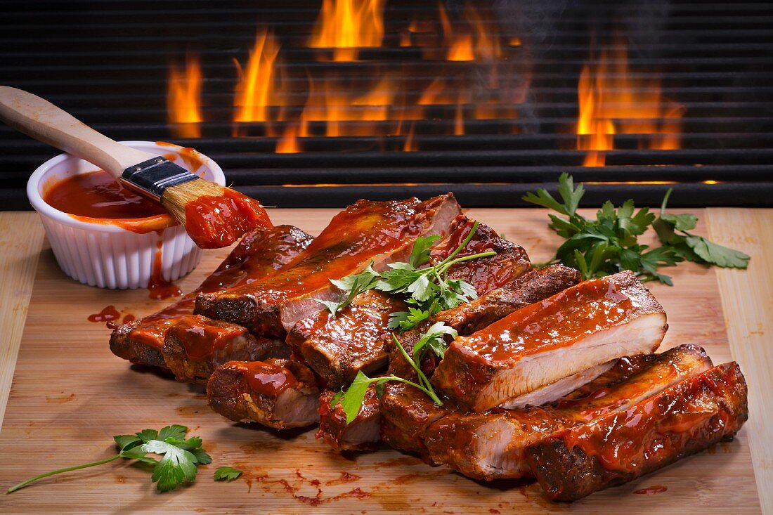 Barbecue spare ribs on a wooden board in front of a fire