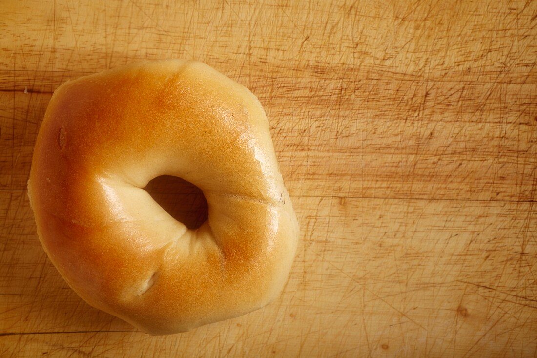 A bagel on a wooden board (seen from above)