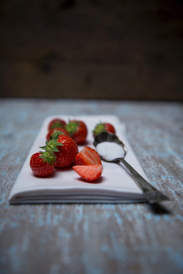Erdbeeren und Löffel mit Zucker