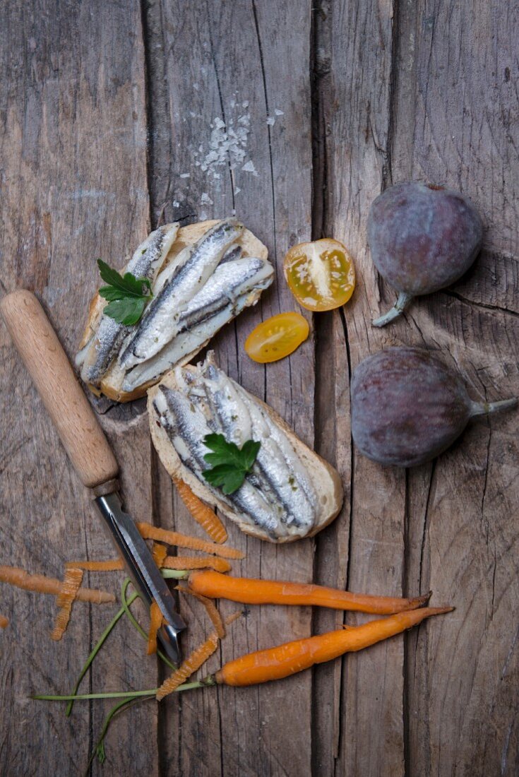 Sardinen auf Brot, Feigen, Meersalz, Petersilie, gelbe Tomaten und Karotten