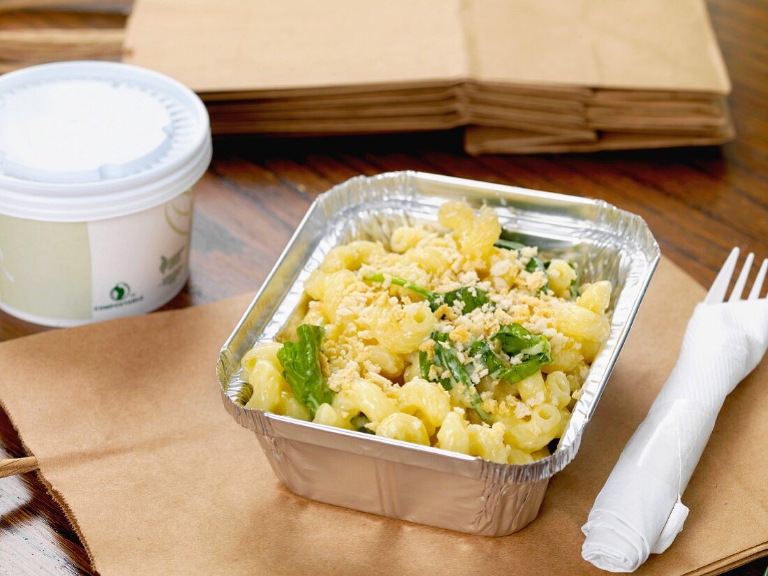 Macaroni and cheese in an aluminium container with plastic cutlery