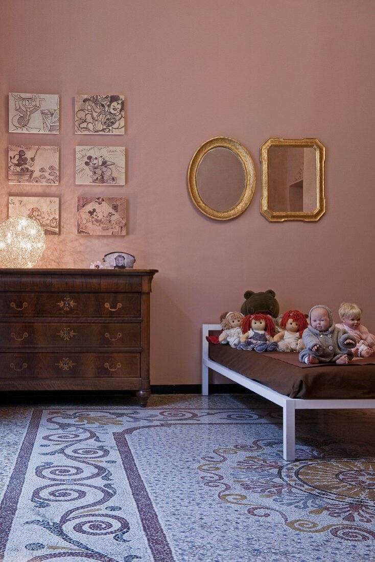 Children's room with old terrazzo floor, antique chest of drawers and dolls on modern bed