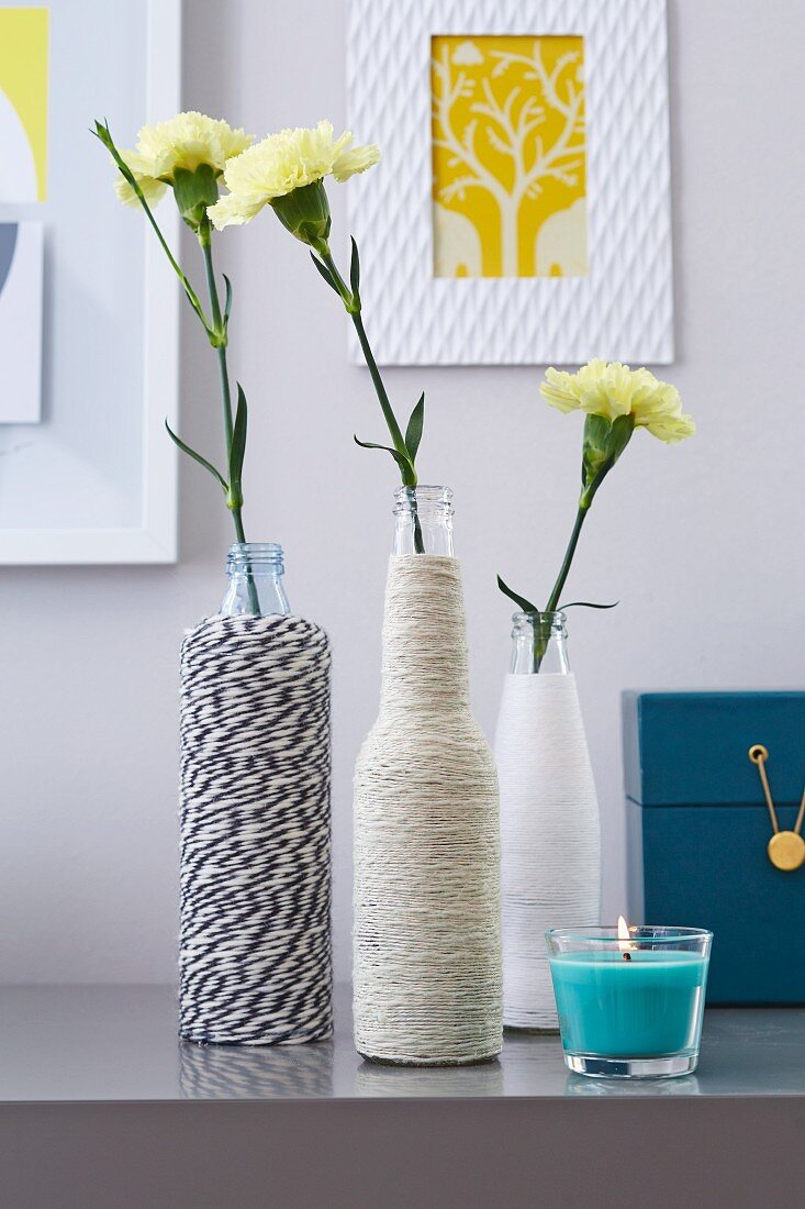 Yellow carnations in DIY vases made from bottles wrapped in twine