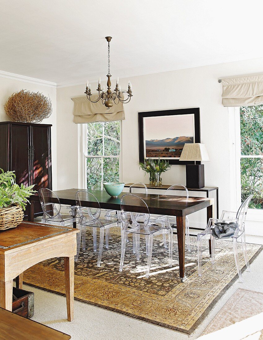 Dark wooden table, Ghost chairs and Persian rug in eclectic dining room