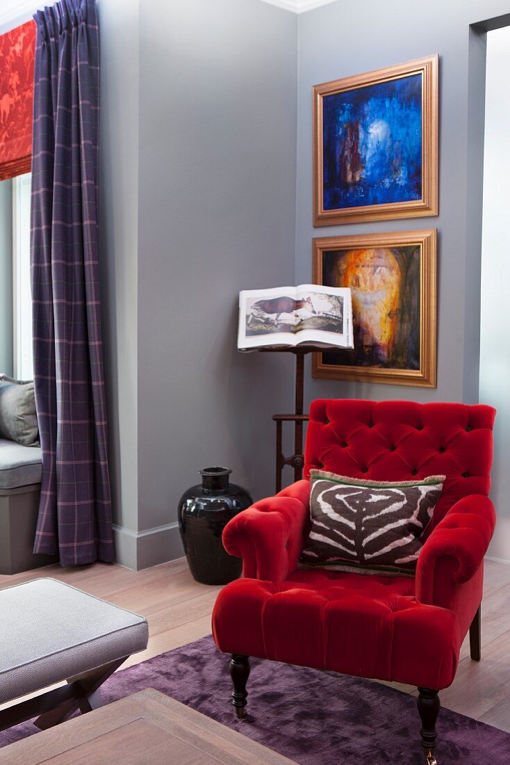 Sessel mit rotem Samtbezug vor Zimmerecke, Bilder mit goldenem Rahmen an grau getönter Wand