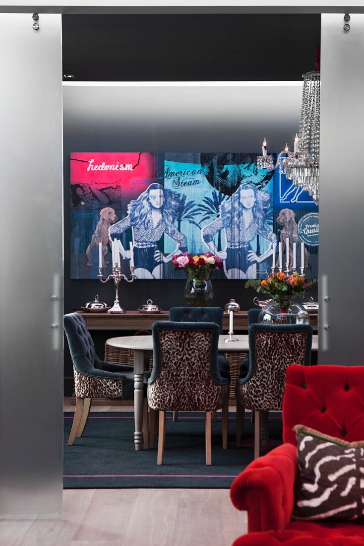 Leopard-print chairs around table in dining room painted grey with modern artwork on wall