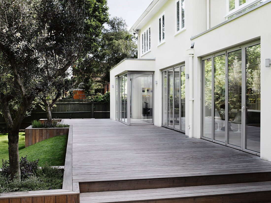 Wooden terrace adjoining contemporary house with glass terrace doors