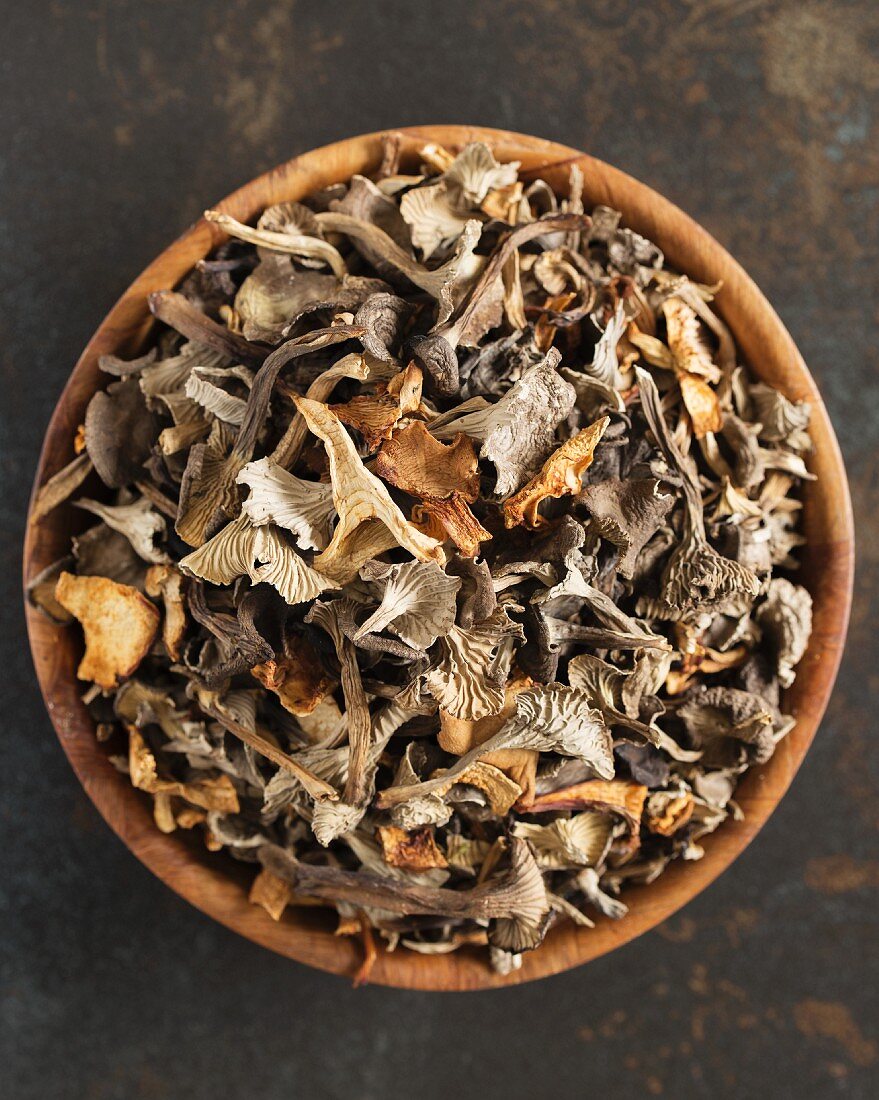 Dried mushrooms in a wooden bowl (seen from above)