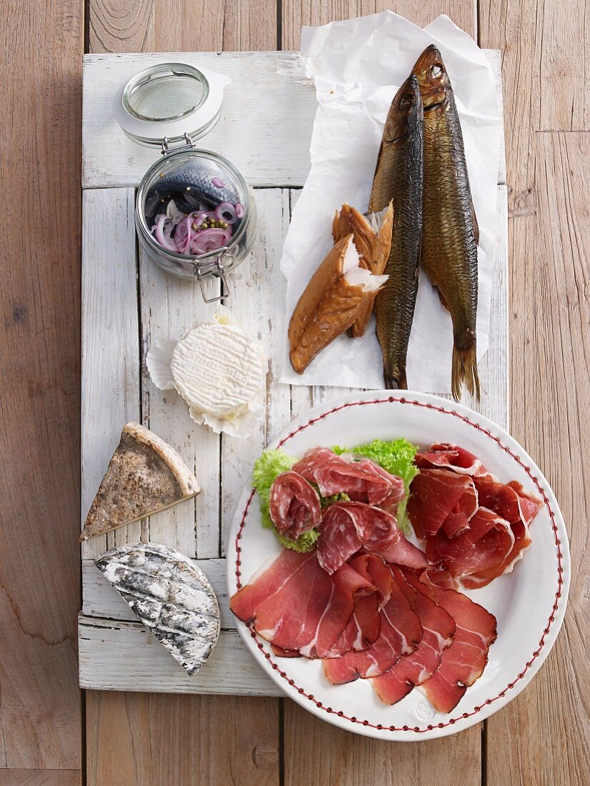 A plate of cold cuts featuring salami, raw ham, smoked fish and cheese for brunch