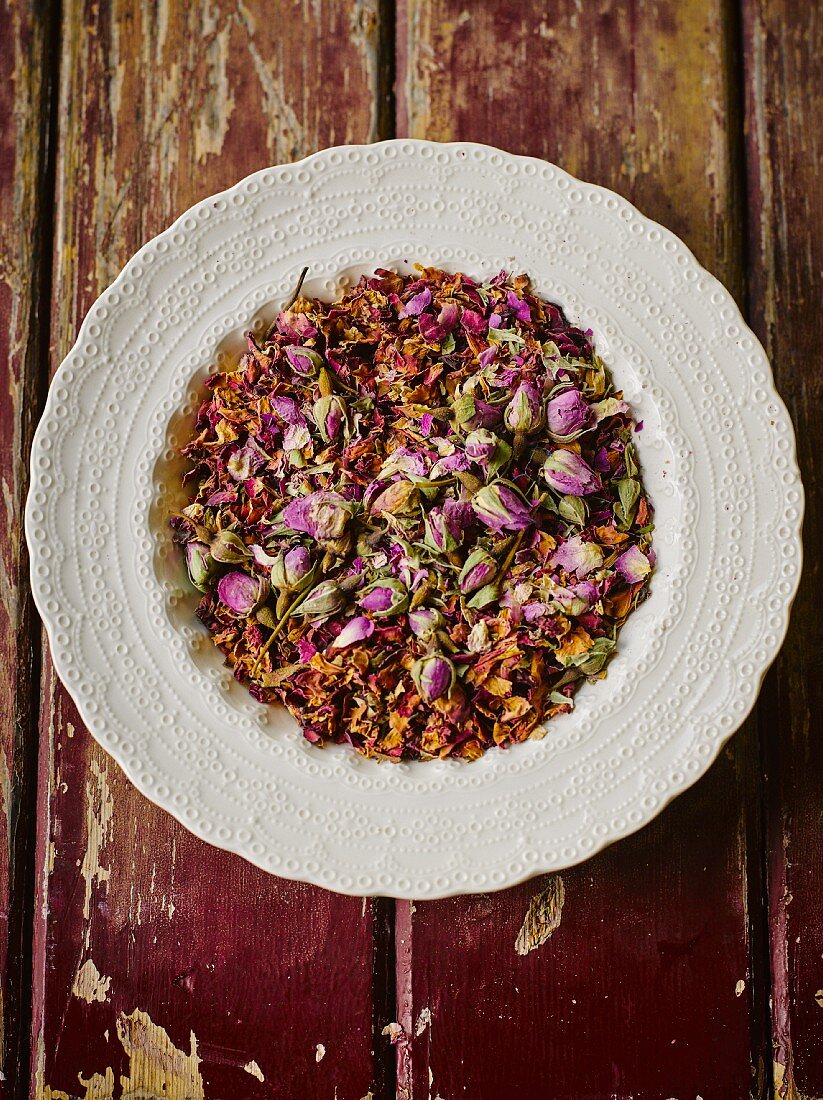 Dried rose buds and petals on a plate (seen from above)