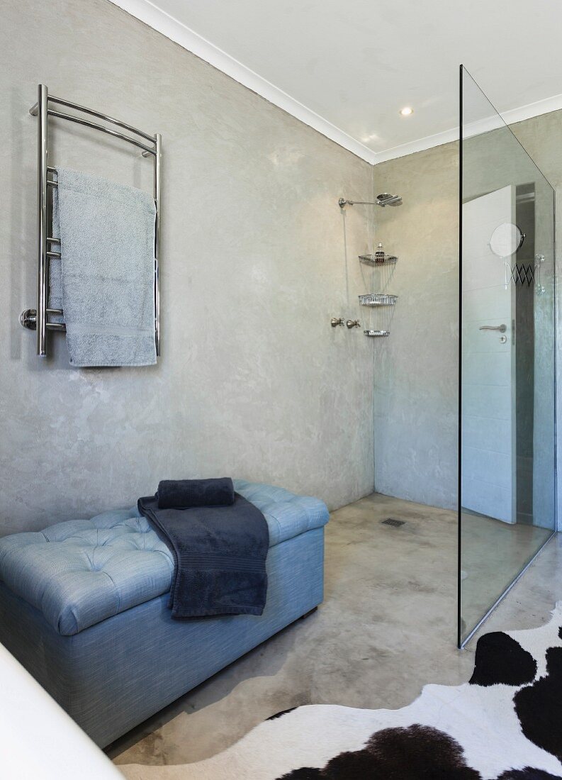Betonboden und marmorierte Wand in puristischem Bad mit begehbarer Dusche und Polsterbank