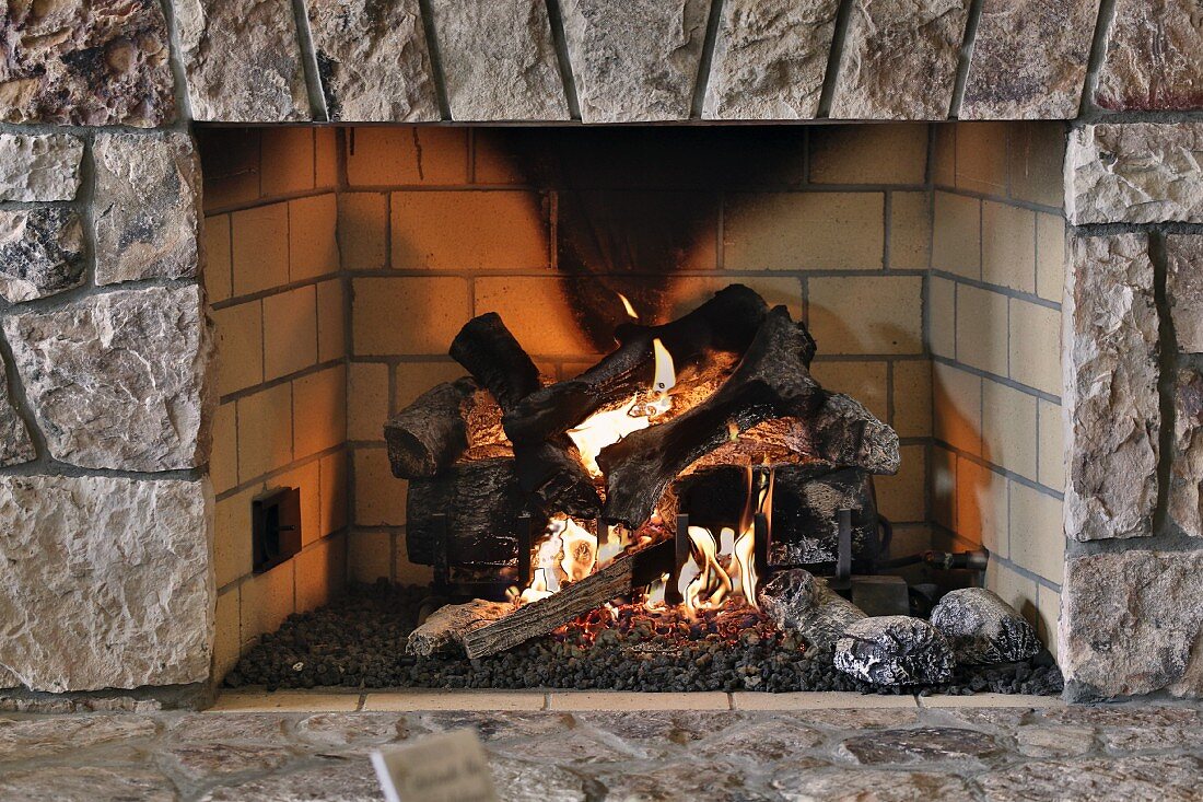 Fire in rustic open fireplace with stone surround