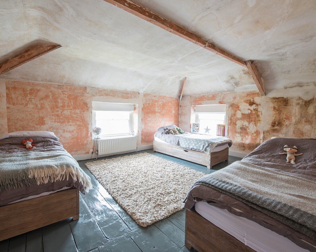 Drei Betten mit Kuscheltier in renoviertem, historischem Dachraum mit Wand-Patina