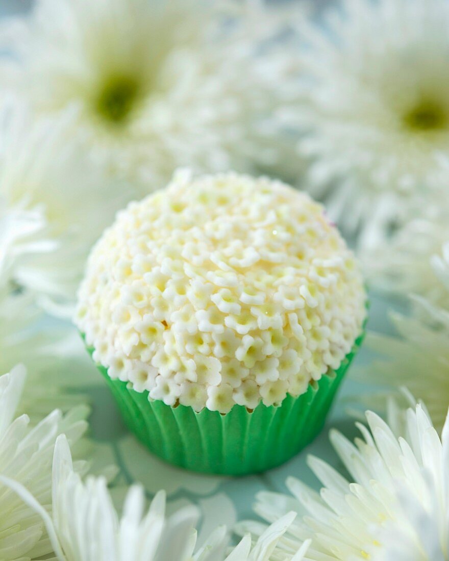 An elderflower cupcake with white fondant flowers