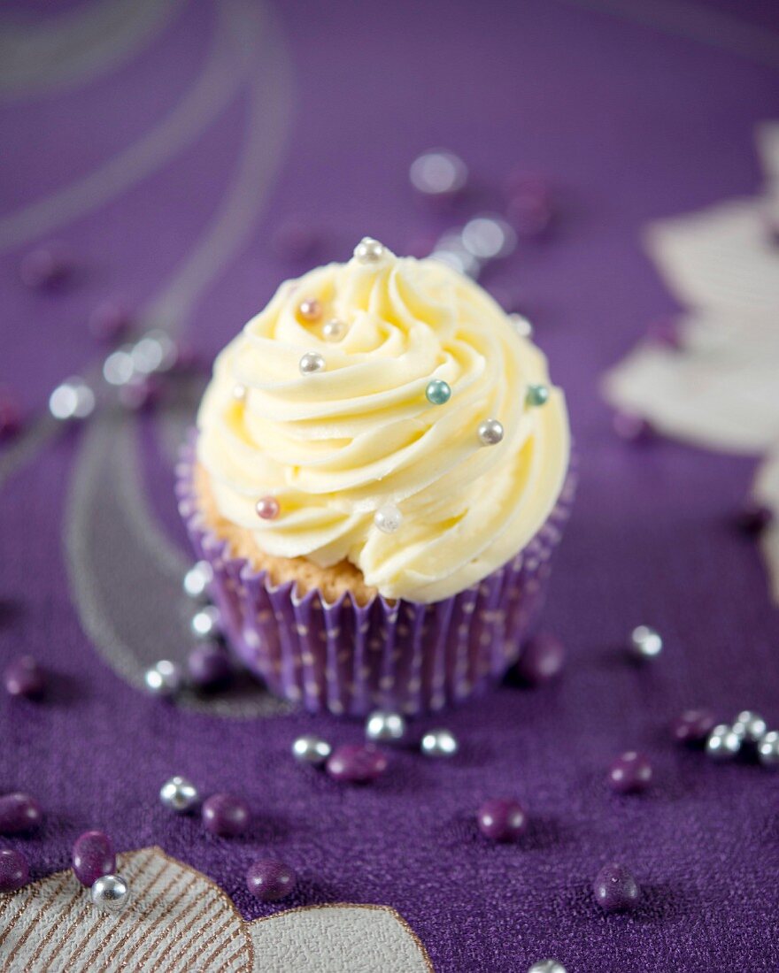 A cupcake with vanilla butter cream and silver sugar pearls