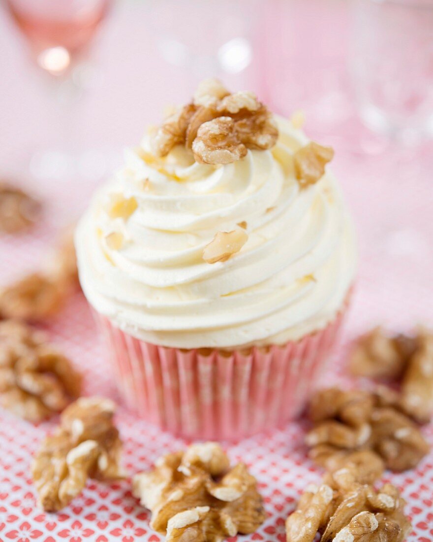 A vanilla cupcake with whipped cream and walnuts
