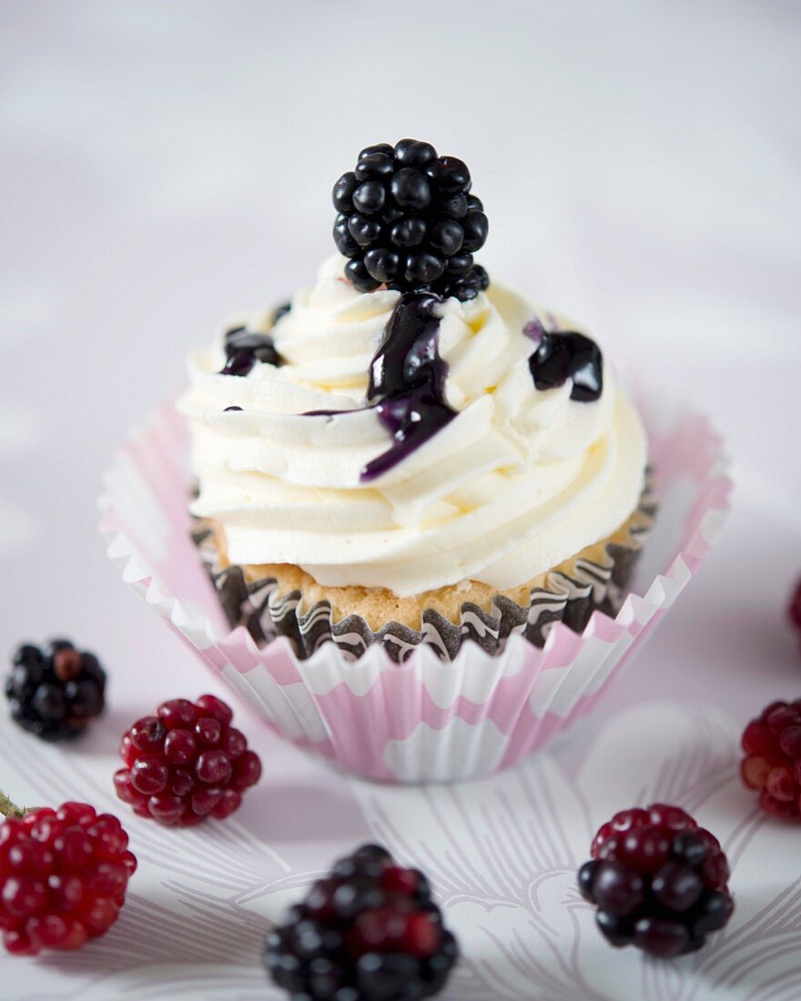 A blackberry cupcake with blackberry sauce