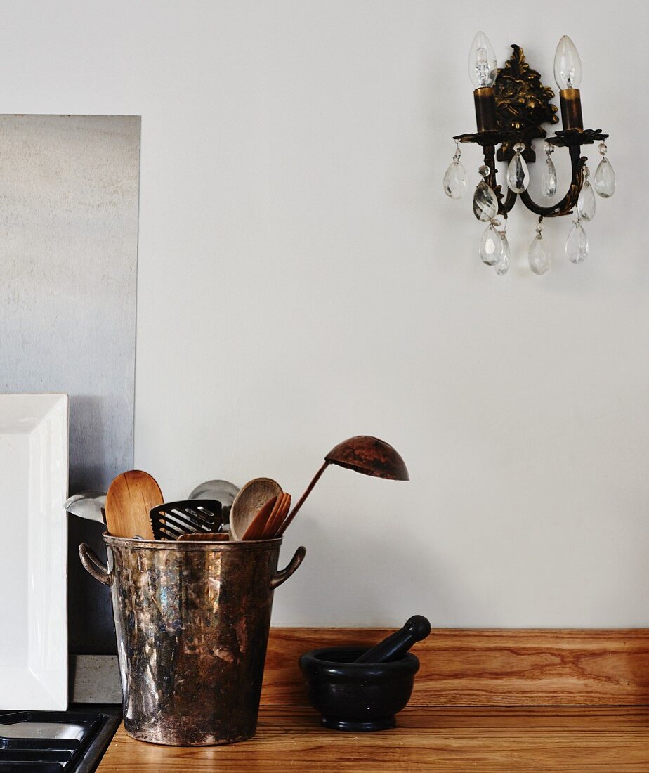 Vintage metal pot of wooden spoons and ladles on wooden worksurface