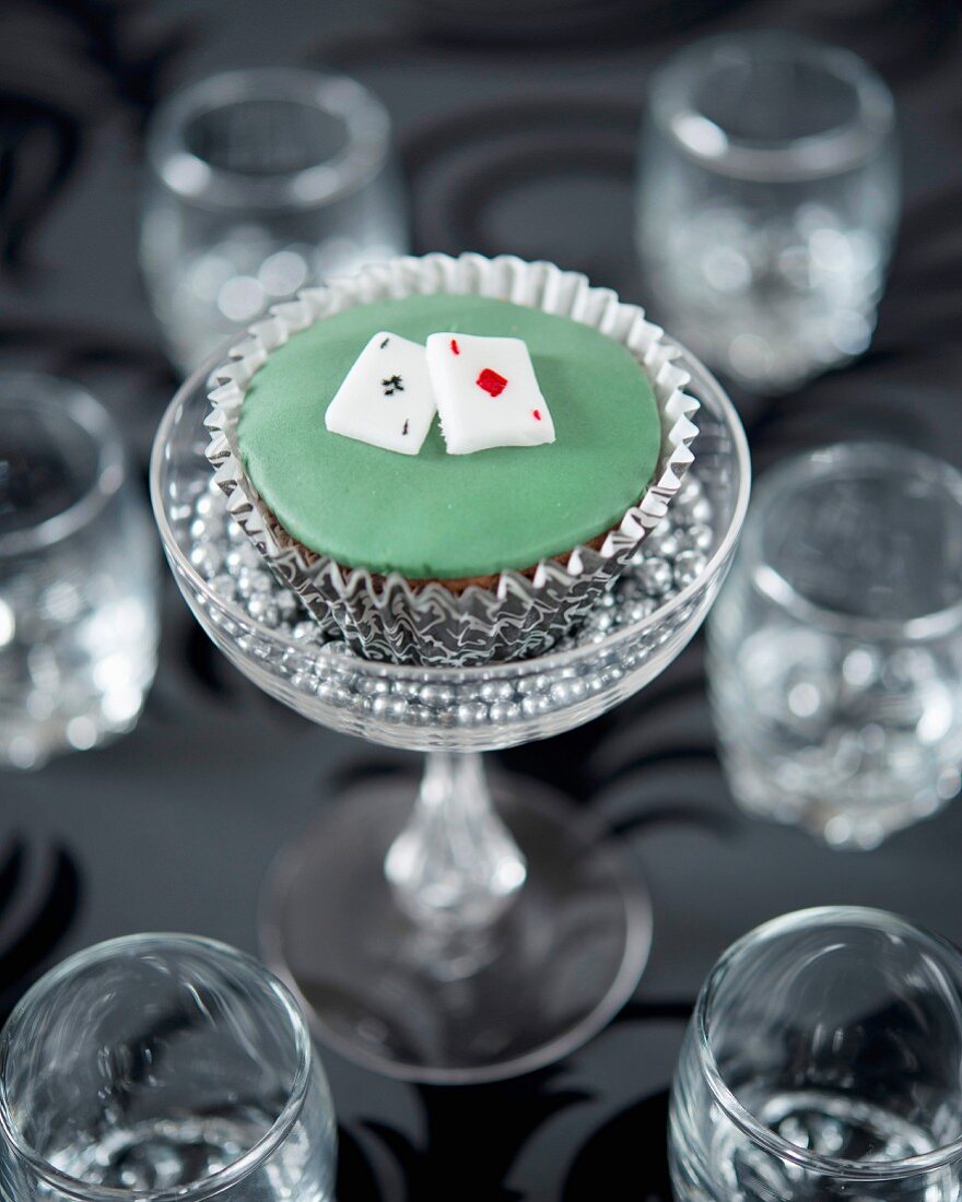 A cupcake decorated with playing cards in a glass