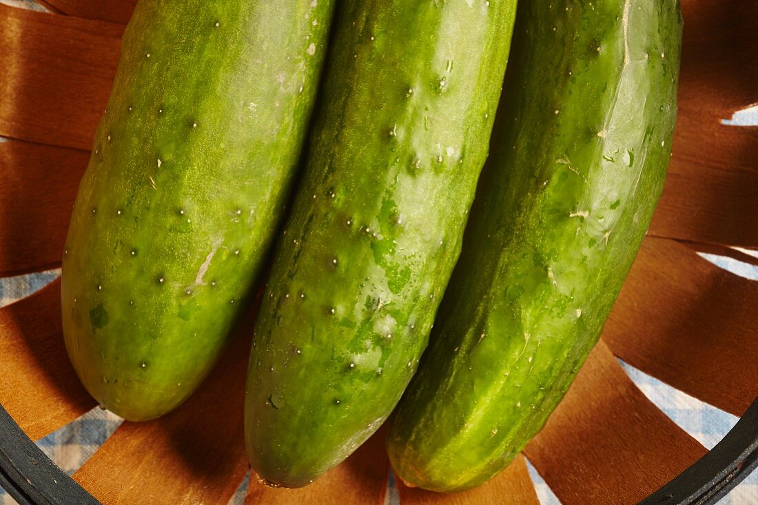 Three fresh cucumber in a wooden basket