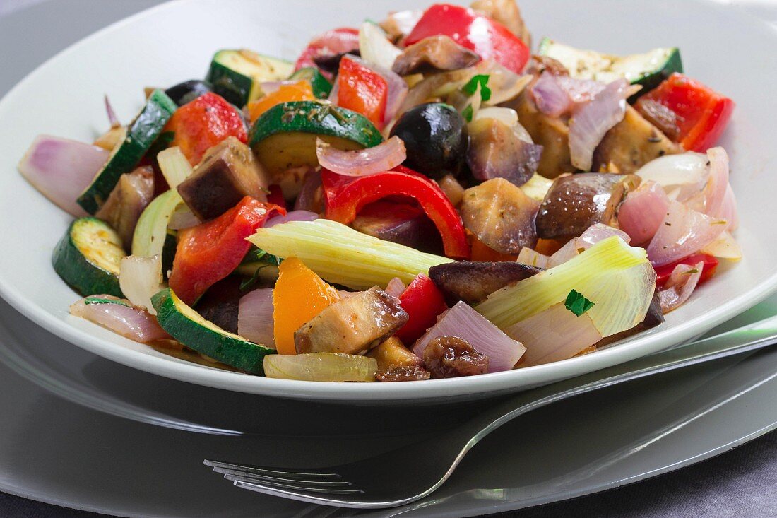 Caponata mit Zucchini, schwarzen Oliven, Zwiebeln, roter und gelber Paprika, Auberginen und Stangensellerie