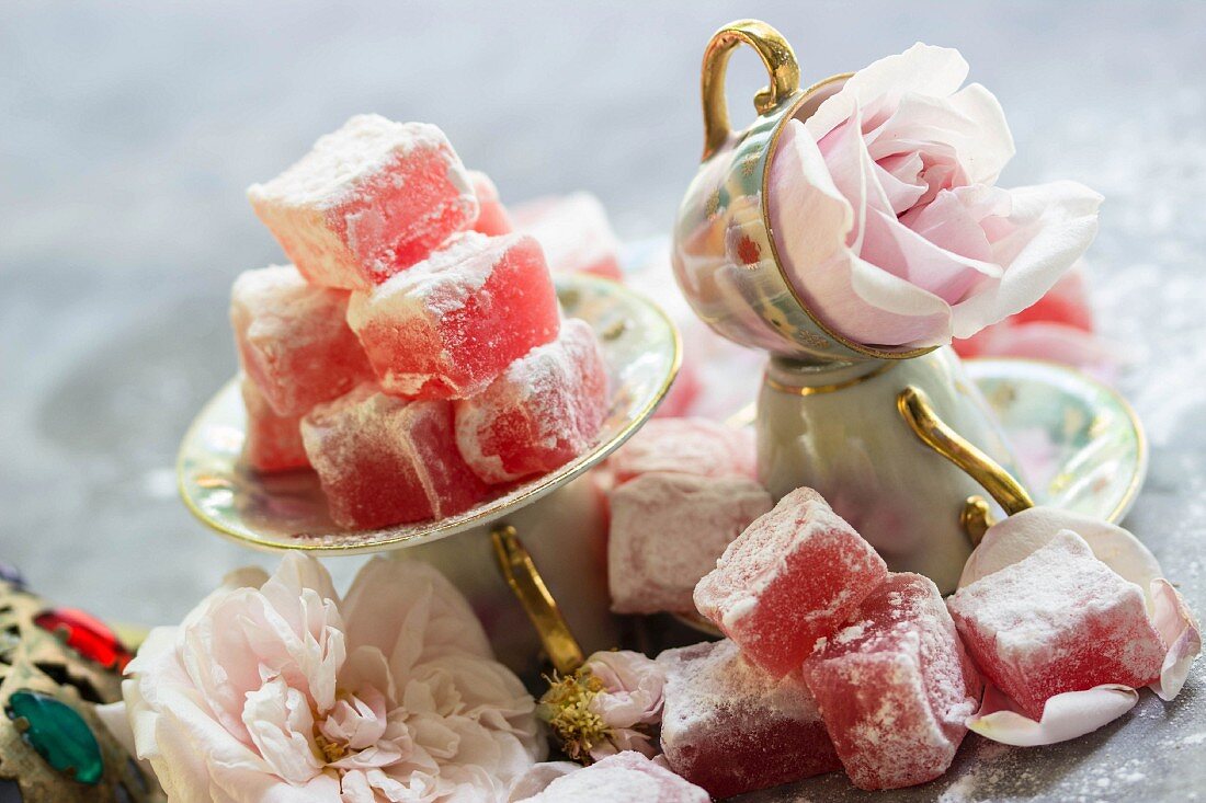 An arrangement of Turkish rose jelly with icing sugar in mocha cups and small saucers with roses in between