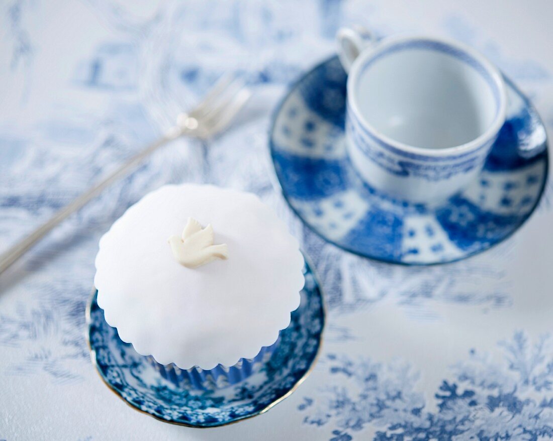 A white cupcake decorated with a fondant bird