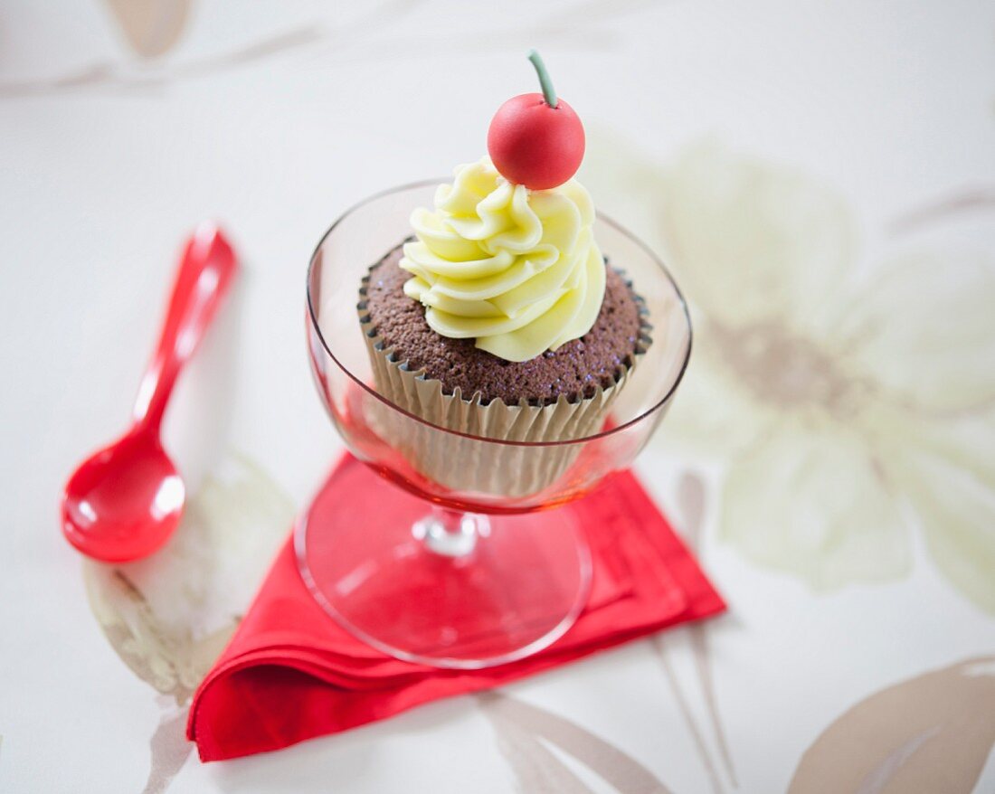 A chocolate cupcake decorated with a fondant cherry