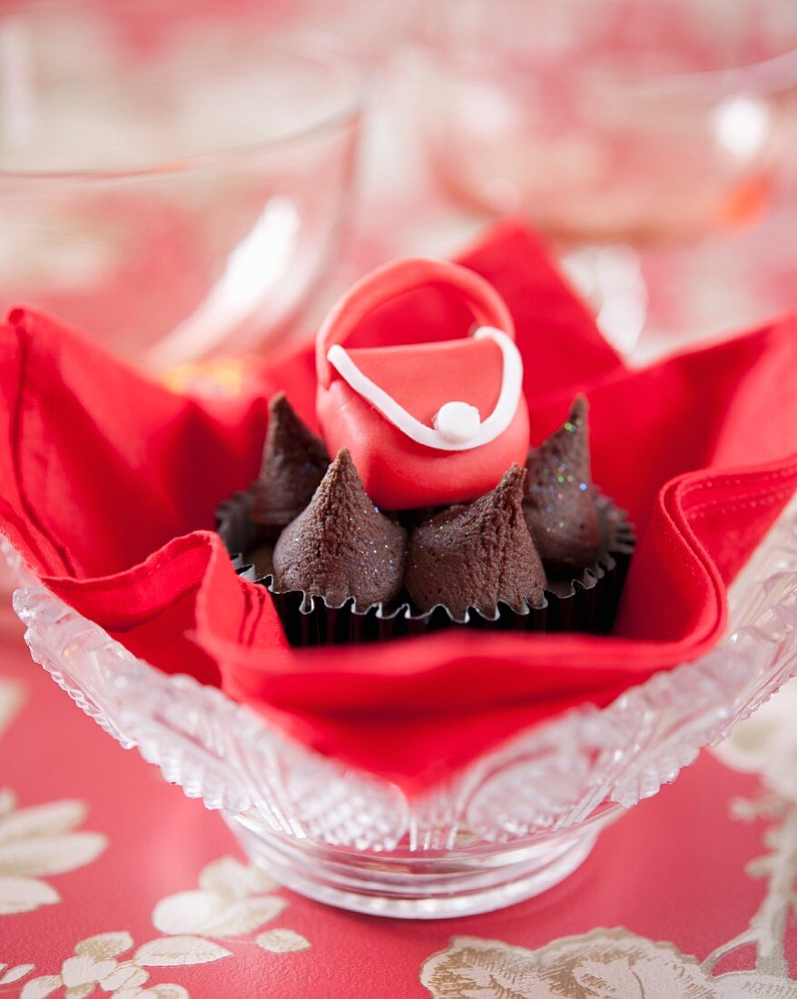 A chocolate cupcake decorated with a red fondant handbag