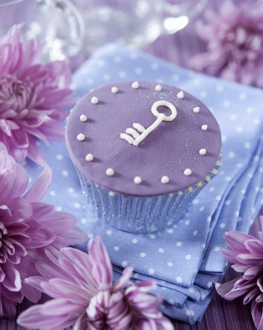 A purple cupcake decorated with a key