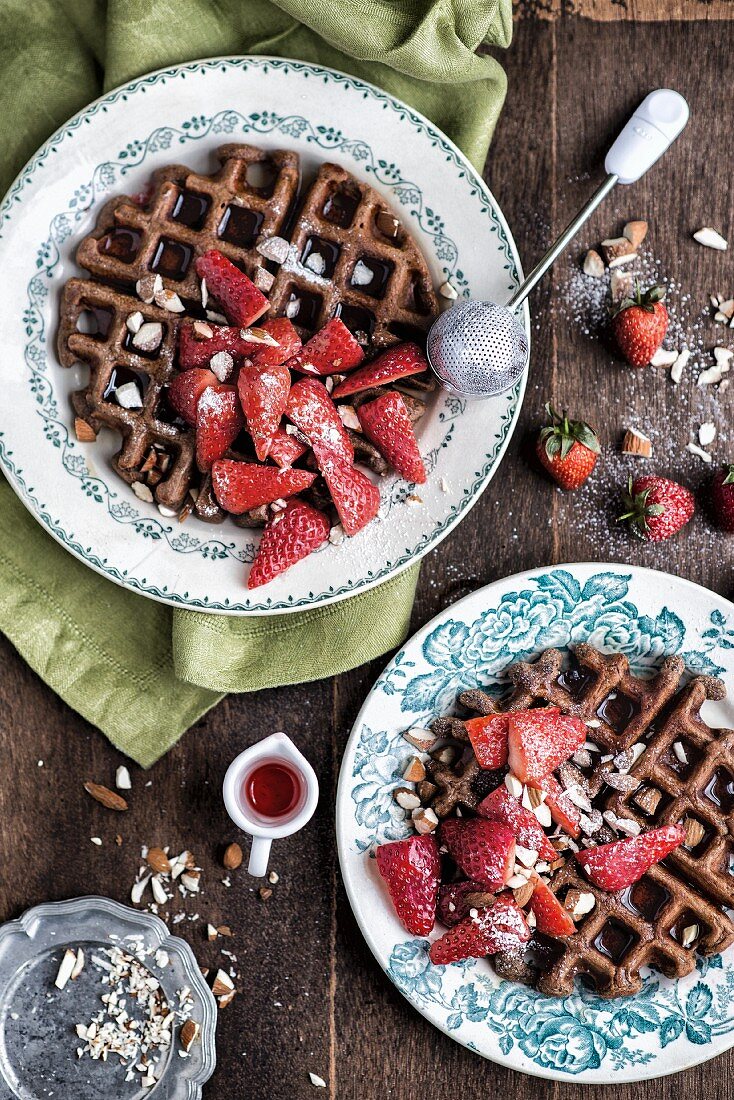 Banana and oat waffles with strawberries and maple syrup for breakfast