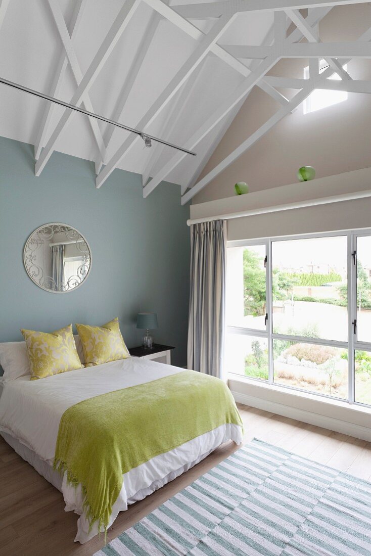 Modern attic bedroom with exposed roof structure painted white