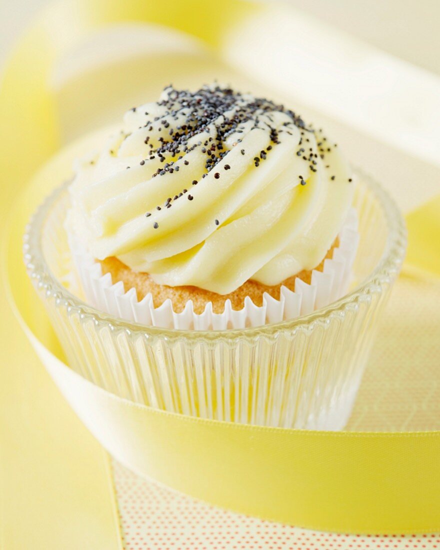 A cupcake with lemon butter cream and poppy seeds