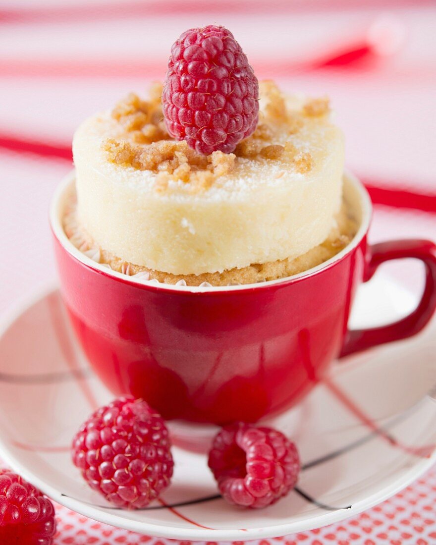 A cheesecake cupcake with raspberries in a red cup