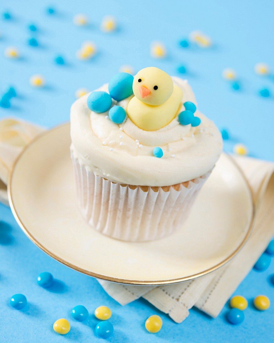 A cupcake decorated with butter cream and a fondant duckling