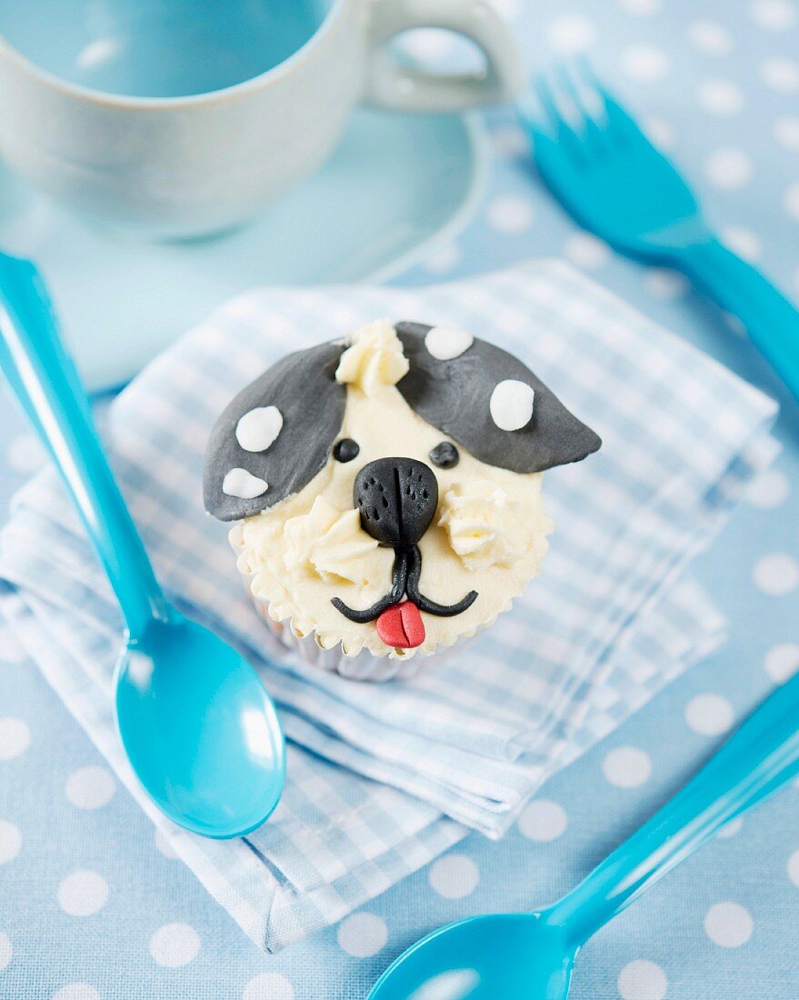 A cupcake decorated with a fondant dog face