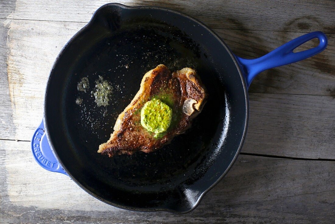 Steak with herb butter in a pan (seen from above)