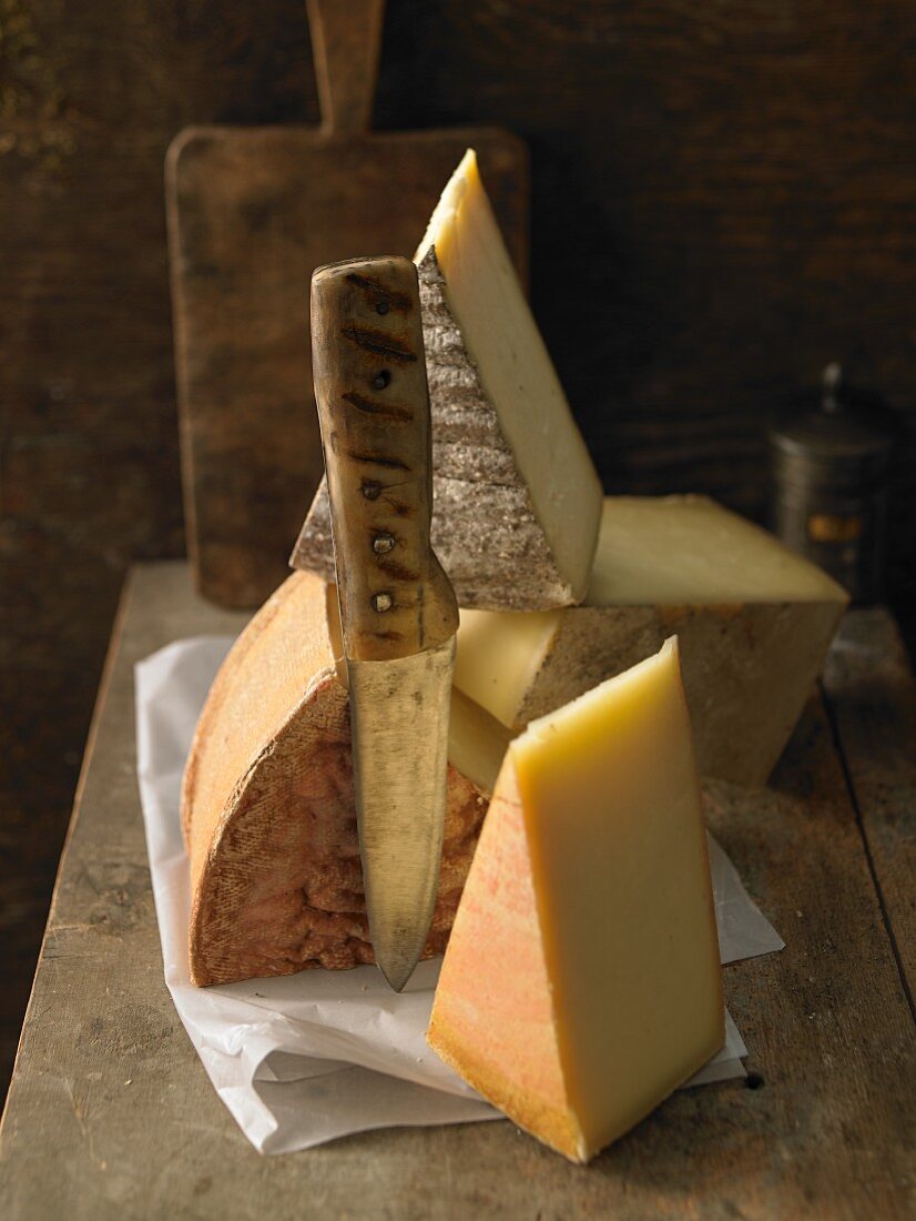 Verschiedene Käsesorten auf Holzbrett mit Messer