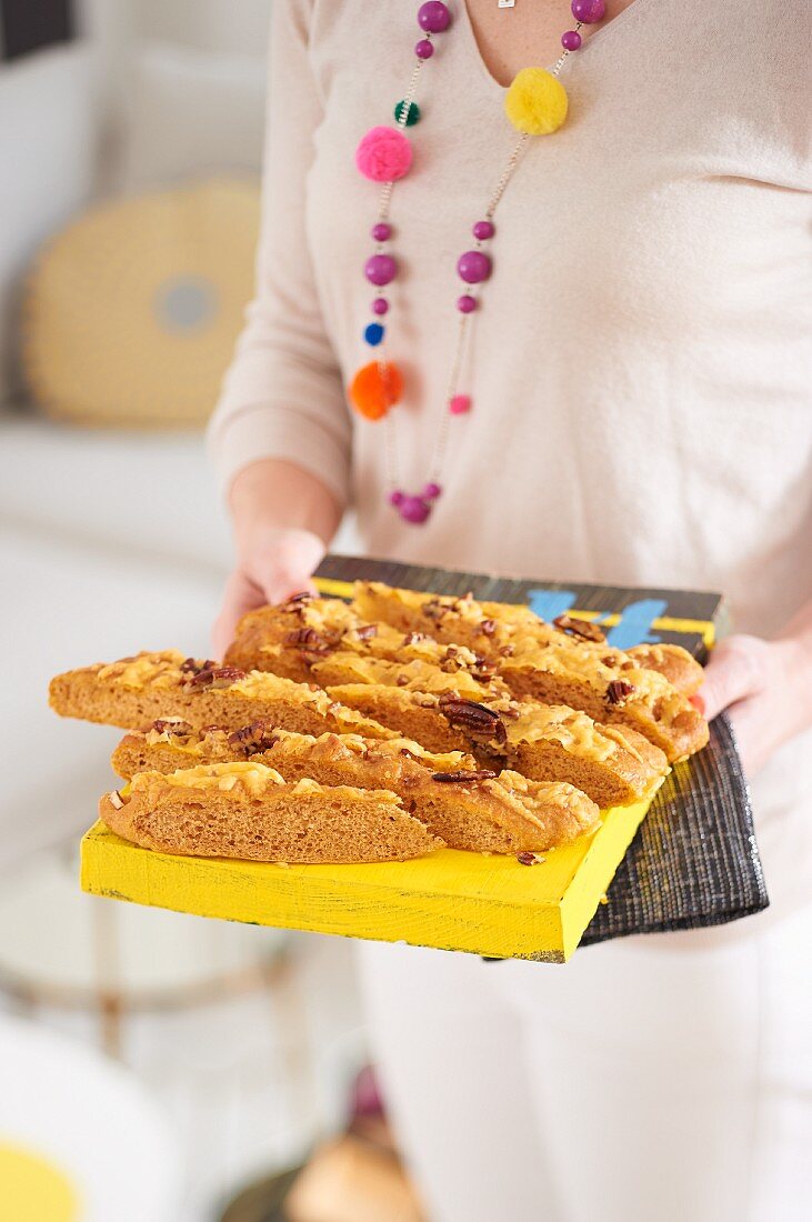 A woman serving BBQ focaccia with nuts and Cheddar cheese