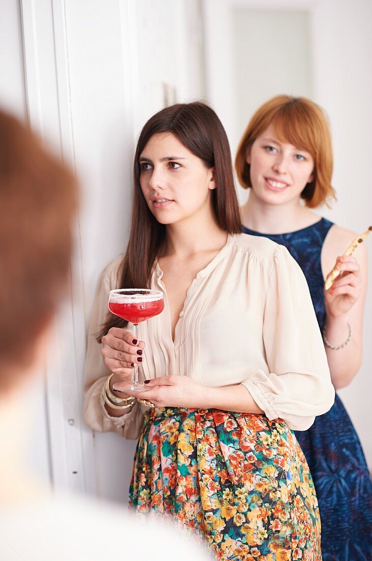 Frau hält ein Glas Virgin-Grapefruit-Margarita bei einer Party