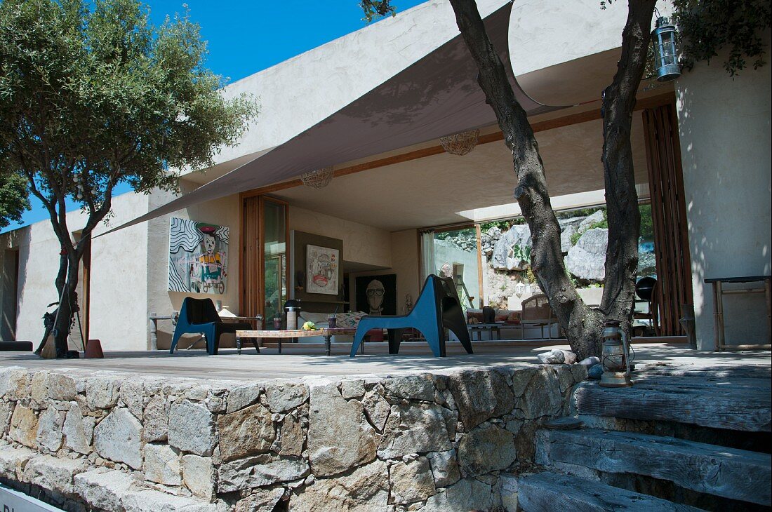 Gemauerte Terrasse mit Olivenbäumen und modernen Stühlen aus Kunststoff